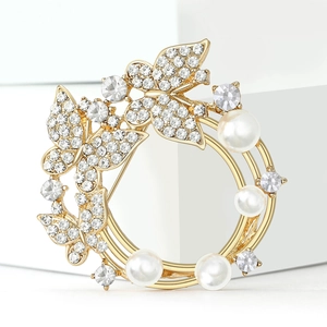 Broche couronne papillon dorée élégante avec strass et perles sur fond blanc pur