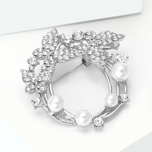 Détail d'une broche couronne argentée avec strass scintillants et perles blanches