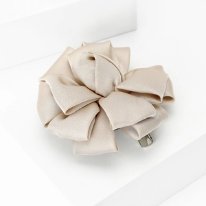 Detail of champagne gold silk ribbon fabric flower with metallic clip on white stand