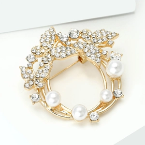 Détail macro d'une broche florale dorée avec des strass blancs et des perles élégantes