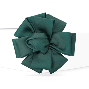 Macro detail of a dark green fabric flower brooch with ribbed texture and layered petals