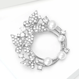 Vue détaillée d'une broche couronne florale argentée avec perles, cristaux et papillons