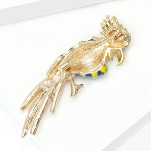 Close-up of parrot brooch back showing the gold metal pin and safety clasp mechanism