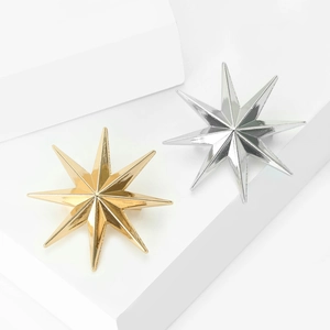 Makro-Detail minimalistischer Gold- und Silber-Sternbroschen mit poliertem Finish