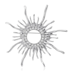 Silver hollow sunburst brooch with crystal rhinestones on a reflective surface
