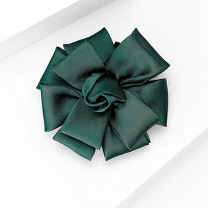 Detailed macro view of dark green fabric flower brooch with ribbed silk texture