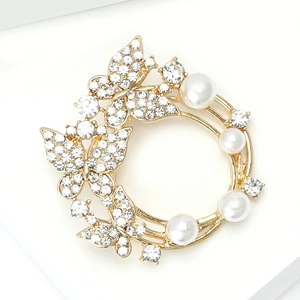 Vue macro détaillée d'une broche couronne dorée avec strass étincelants et perles blanches