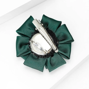 Detail of dark green fabric flower brooch with silver alligator clip and safety pin back