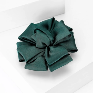 Close-up of dark green satin fabric flower brooch with layered bow craftsmanship