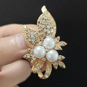 Gros plan d'une élégante broche fleur avec strass étincelants et perles en main