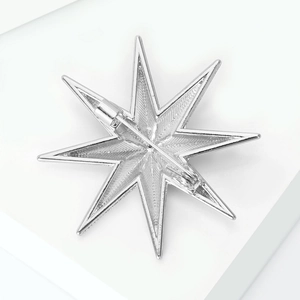 Macro shot of silver eight-pointed star brooch back showing secure pin and safety clasp