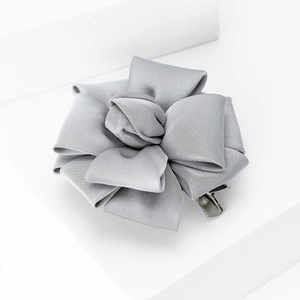 Detailed close-up of a silver-grey satin ribbon brooch with an elegant floral design