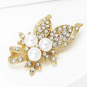 Vue macro d'une broche papillon dorée avec perles nacrées et cristaux étincelants