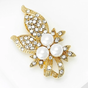 Détail de l'élégante broche papillon dorée avec strass brillants et perles blanches