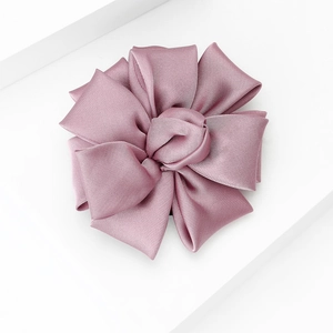Detailed macro view of the dusty pink satin fabric texture and pleated flower layers