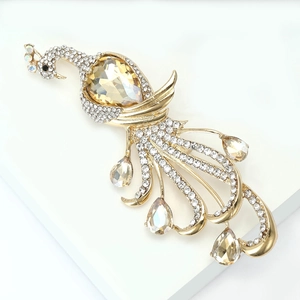 Close-up of golden peacock brooch with sparkling champagne rhinestones on a white stand