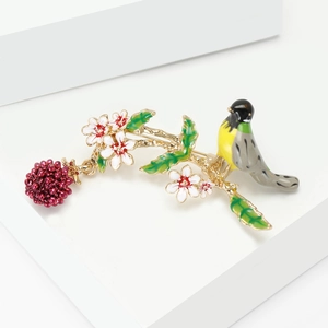 Detail der Emaille-Vogelbrosche auf goldenem Zweig mit weißer Blume und roter Beere