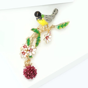 Makroaufnahme einer Emaille-Vogelbrosche auf einem Goldzweig mit Blumen und Beeren-Detail