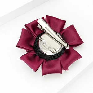 Close-up of the burgundy fabric flower brooch back with metal clip and safety pin