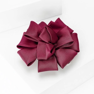 Detailed view of the layered burgundy satin ribbon flower brooch on white pedestal