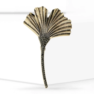 Elegant gold ginkgo leaf brooch with detailed veins and black rhinestones on white base