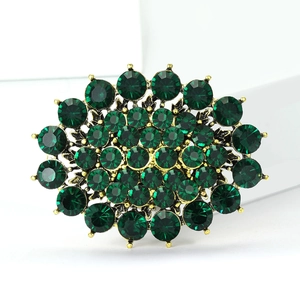 Detailed view of an oval emerald green rhinestone brooch with vintage gold alloy setting