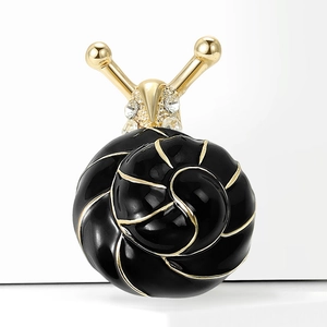 Détail de broche escargot avec émail noir, métal doré et strass brillants sur fond neutre