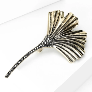 Macro view of vintage gold ginkgo leaf brooch featuring black rhinestones and fine textures