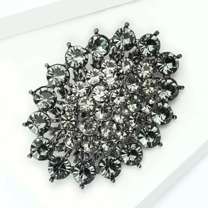 Detailed 45-degree angle view of vintage sunburst brooch with dark grey rhinestones