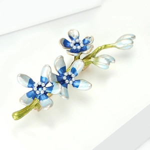 Detailed close-up of blue and white enamel flower brooch with branch and pearls