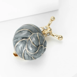 Détail macro d'une broche escargot en émail avec texture marbre gris et métal doré