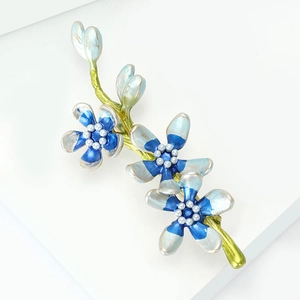 Detailed close-up of enamel flower brooch with blue gradient petals and white pearl centers