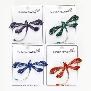 Detailed macro view of four colorful dragonfly brooches with enamel wings and gemstones