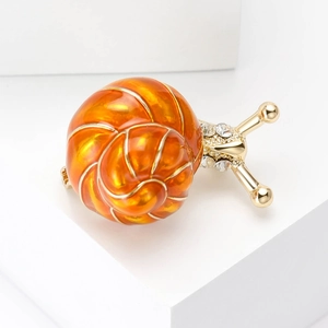 Détail d'une broche escargot en émail avec dégradé orange et cristaux scintillants