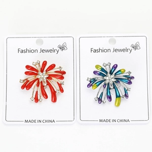 Detailed macro view of dual firework brooches featuring red and blue gradient enamel finish
