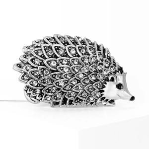 Sparkling hedgehog brooch with silver alloy scales and clear crystals on white background