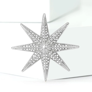 Elegant silver eight-pointed star brooch with sparkling rhinestones on a white pedestal