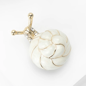 Détail de la broche escargot en émail blanc avec des cristaux brillants et dorés