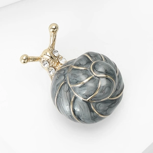 Détail d'une broche escargot avec base dorée, coque en émail et strass brillants