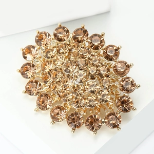 Detail of vintage gold alloy brooch with sparkling champagne rhinestones on white stand