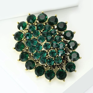 Macro shot of vintage emerald rhinestone brooch with antique gold plated setting details