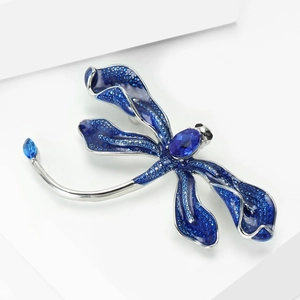 Detailed view of dragonfly brooch featuring deep blue gemstones and silver plating