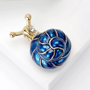 Détail de broche escargot dorée avec coque en émail bleu et incrustation de zircon