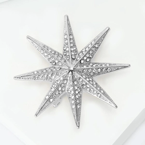 Macro detail of silver octagonal star brooch with sparkling rhinestones and metal pin clasp
