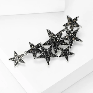 Detail of star-shaped brooch with black rhinestones on a white geometric platform