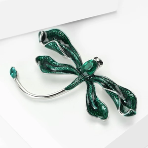 Macro detail of dragonfly brooch with green gems and shimmering wing texture
