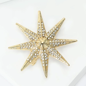 Detailed view of gold starburst brooch with micro-pave crystals and back pin clasp
