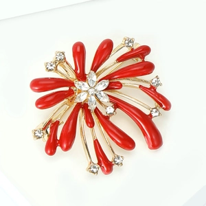 Detail of red enamel flower brooch with sparkling crystals on a golden alloy base