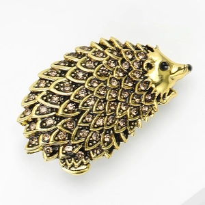 Detail of vintage gold hedgehog brooch with amber rhinestones on a white background