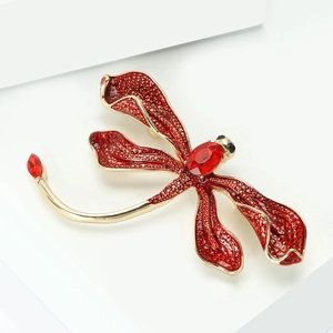 Detailed close-up of a golden dragonfly brooch with faceted red crystal and inlaid wings